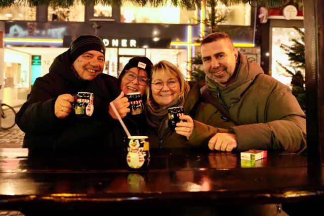 Eine Gruppe Weihnachtsmarktbesucher mit Glühwein in den Händen