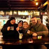 Eine Gruppe Weihnachtsmarktbesucher mit Glühwein in den Händen