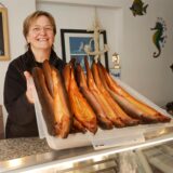 Christiane Kuhnke präsentiert in Andy’s Fischhütte geräucherte Fische.