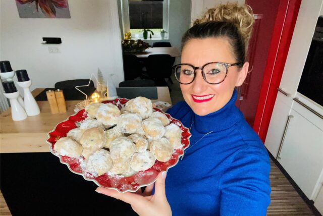 Angela Küntzle hält einen Teller mit Stollenkonfekt in die Kamera und lächelt dabei.