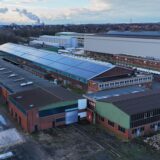 Mehrere Industriegebäude am Waldrand.