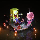Menschen mit leuchtenden Flößen im Dunkeln im Wasser.