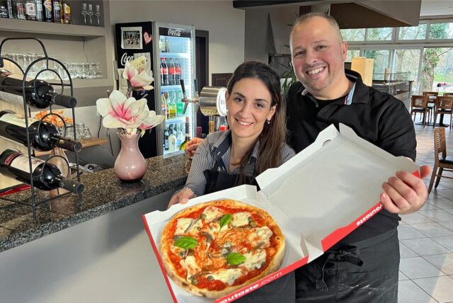 Liridona und Arben Abazi präsentieren eine Pizza Italia.
