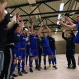 Fußballspieler feiern mit einer Trophäe.