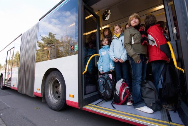 Kinder stehen in der Tür eines Schulbusses.