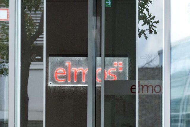 Das Logo des Unternehmens Elmos ist durch eine automatische Schiebetür zu sehen.