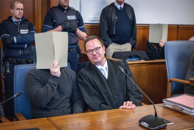 Anwalt Christoph Krekeler sitzt im Gerichtssaal neben dem Polizisten Fabian S., der in Dortmund die tödlichen Schüsse auf Mouhamed Dramé abgefeuert hat.