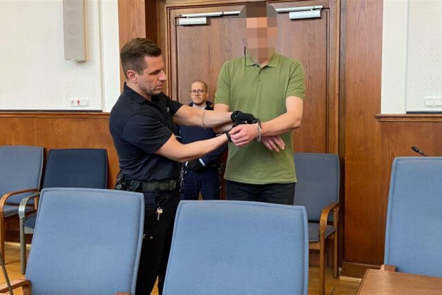 Ein Justizbeamter liegt einem Mann Handschellen an.