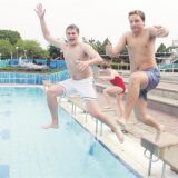 Zwei Männer springen im mittlerweile abgerissenen Freizeitbad Massen in das Außenbecken.