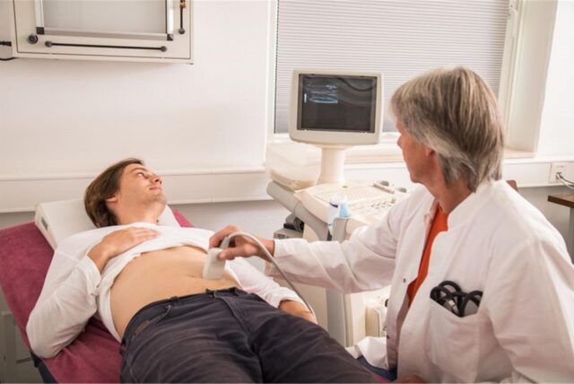 Ein Arzt macht in seiner Praxis ein Ultraschall von dem Bauch eines Patienten.