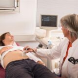 Ein Arzt macht in seiner Praxis ein Ultraschall von dem Bauch eines Patienten.