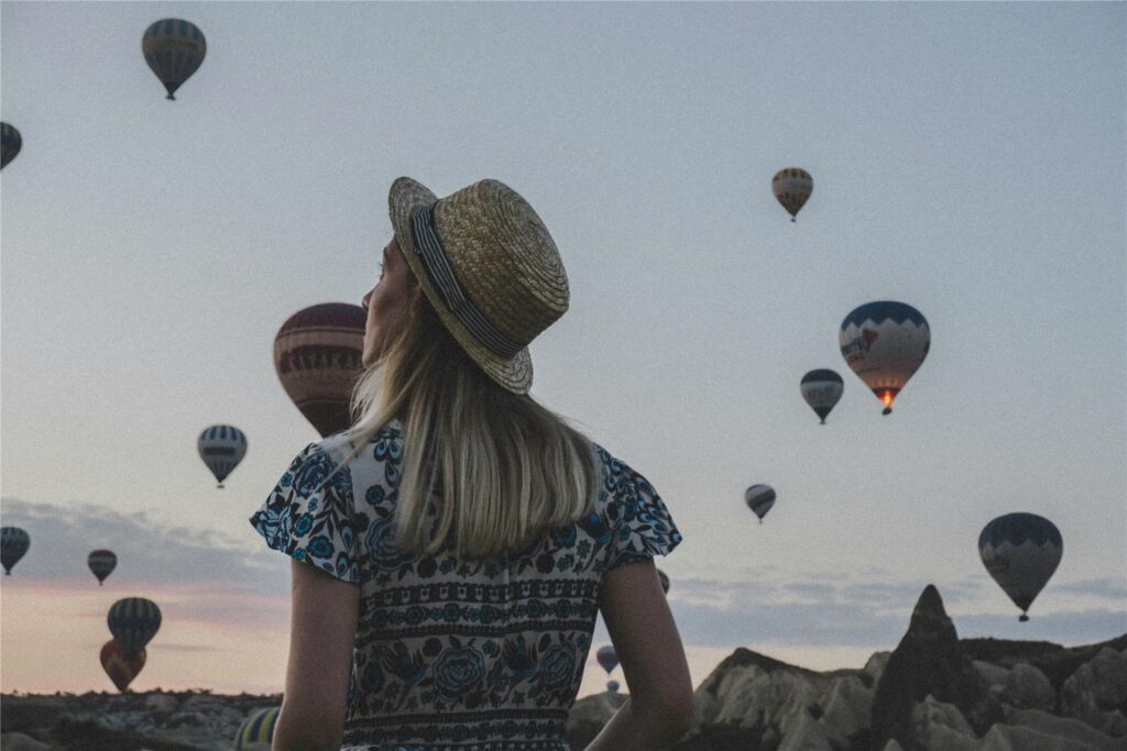 Eine Frau beobachtet bei einer Reise die aufsteigenden Heißluftballons in Kappadokien.