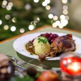 Ein klassisches Gericht an Heiligabend und den Weihnachtsfeiertagen ist Ente mit Rotkohl und Klößen. Serviert wird das Gericht hier auf einem grünen Tischset.