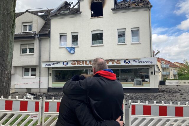 Ein Ehepaar betrachtet ein abgebranntes Haus.