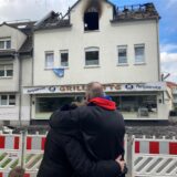 Ein Ehepaar betrachtet ein abgebranntes Haus.
