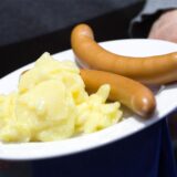 Würstchen mit Kartoffelsalat liegen auf einem Teller.