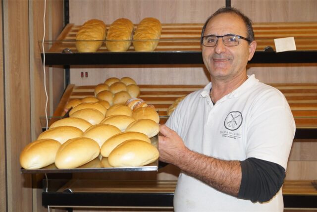 Blerand Osmanaj von der Balkan Bäckerei in Rünthe hält ein Blech mit Brötchen in die Kamera.