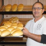 Blerand Osmanaj von der Balkan Bäckerei in Rünthe hält ein Blech mit Brötchen in die Kamera.