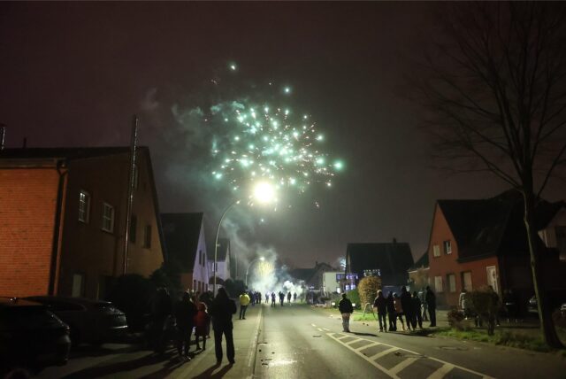 Menschen schauen auf der Straße buntes Feuerwerk an.