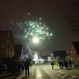 Menschen schauen auf der Straße buntes Feuerwerk an.