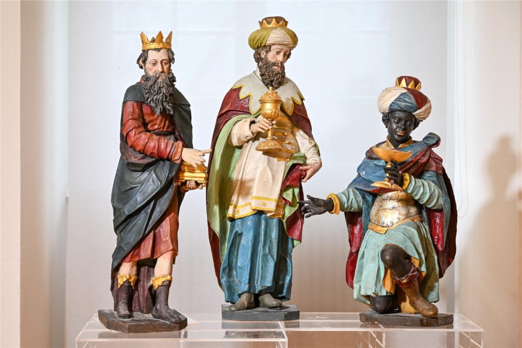 Drei Figuren, die die Heiligen Drei Könige darstellen, stehen in einer Krippenausstellung.