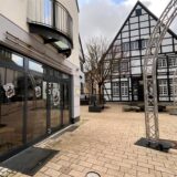 Ein Café-Gebäude in Unna an der Hertingerstraße. Daneben sind noch Lichterbögen vom Weihnachtsmarkt aufgebaut. Im Hintergrund steht das Fachwerkgebäude des Seniorentreffs Fässchen.