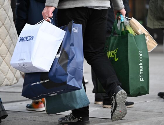 Ein Mann geht am verkaufsoffenen Sonntag mit Tüten bepackt shoppen.