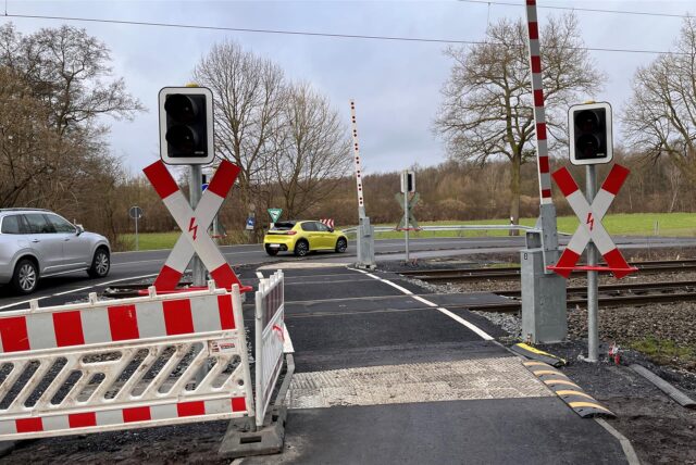Zwei Autos fahren in Unna über den Bahnübergang an der Heerener Straße. Nach Bauarbeiten am Radweg steht vor Ort noch Absperrbaken