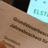 Ein Grundsteuerbescheid  wird vor einen Computerbildschirm