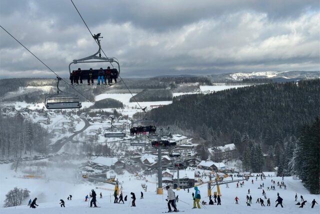 Menschen fahren Ski in Winterberg. Über der Piste sind Lifte.