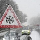 Ein Verkehrschild an der Südring-Brücke warnt vor Gefahr von Schnee- oder Eisglätte auf der Fahrbahn, während Schnee fällt.