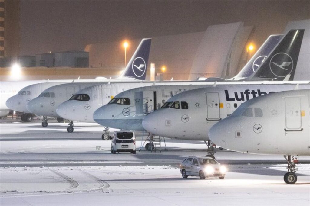 Mehrere Flugzeuge der Lufthansa stehen teils mit Schnee bedeckt auf dem Flughafen Frankfurt. 