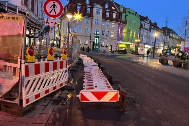 Eine Frau läuft mit einem Regenschirm durch den Wind.