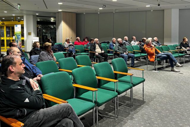 Menschen sitzen auf grünen Stühlen im Stadthaus in Werne.