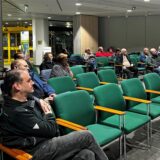 Menschen sitzen auf grünen Stühlen im Stadthaus in Werne.