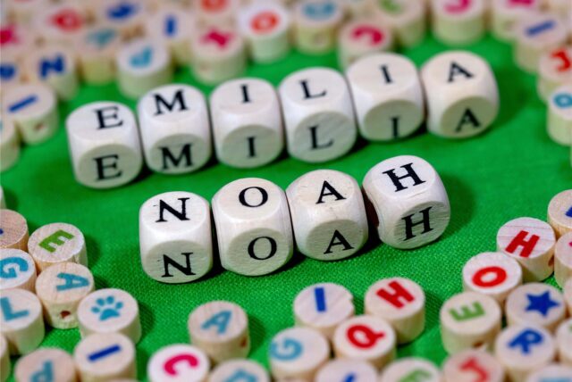 Holzwürfel mit Buchstaben, die die Namen Emilia und Noah ergeben, liegen auf einem Tisch.