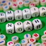Holzwürfel mit Buchstaben, die die Namen Emilia und Noah ergeben, liegen auf einem Tisch.