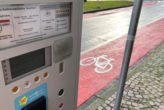 An einem rot markierten Radweg steht ein Parkscheinautomat