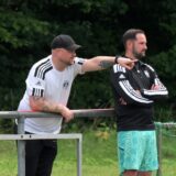 Stephan Ahland zeigt auf das Spielfeld, Sebastian Treppe steht daneben.