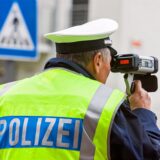 Ein Polizist kontrolliert mit einer Laserpistole die Geschwindigkeit auf einer Straße.