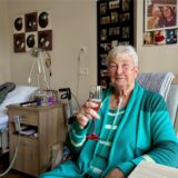 Uschi Pathmann aus Recklinghausen sitzt in einem Zimmer und trinkt aus einem Sektglas