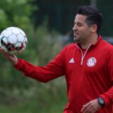 Kurtulus Öztürk hält einen Ball, unter ihm machen Fußballer Liegestütze.