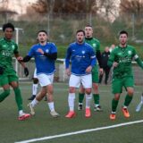 Fußballspieler zweier Mannschaften warten bei einer Standardsituation auf den Ball.