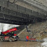 Ein Mann sichert Stahlträger an einem Schwerlastkran.