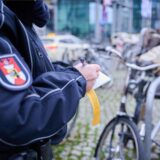 Eine Mitarbeiterin des Ordnungsamts in Berlin beschriftet einen gelben Hinweiszettel, der an einem Fahrrad befestigt wird.