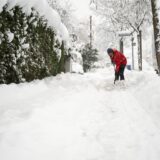 Ein Mann räumt Schnee auf einem Gehweg.