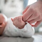 Ein Baby klammert sich an den Finger seiner Mutter.