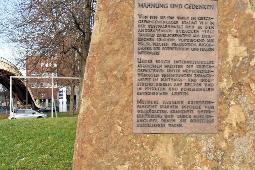 Dieser Mahn- und Gedenkstein erinnert an das Stalag VI D und seine Gefangenen. Das Mahnmal steht an der Brücke in Richtung Lindemannstraße.