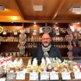 Der Inhaber Daniel Hein steht hinter der Theke seines Cafes. Die Theke ist gefüllt mit Keksen und Lebkuchenherzen.