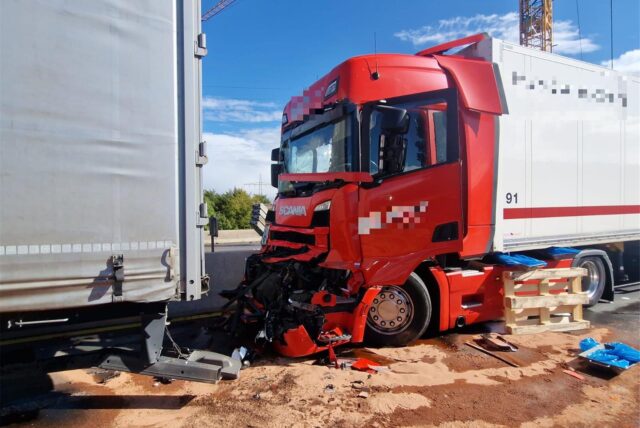 Nach einem Unfall stehen auf einer Autobahn zwei Lkw hintereinander. Ein Fahrzeug ist beschädigt, und rundherum ist Bindemittel verstreut
